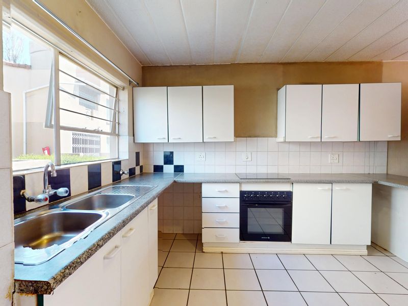 A functional kitchen featuring built-in cabinetry, a double basin sink, and an integrated oven with hob, offering a blank canvas for modern updates.