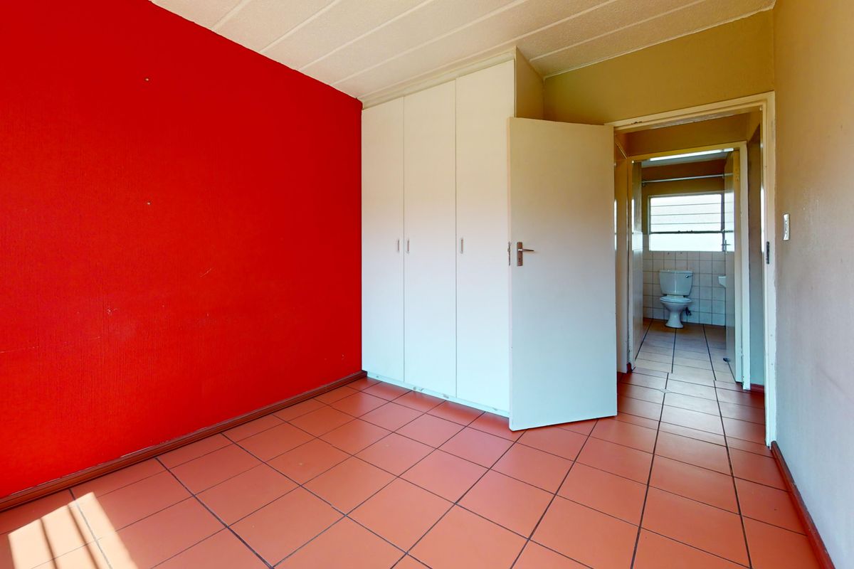 An empty bedroom featuring tiled flooring, built-in cupboards, and direct access to an en-suite bathroom.