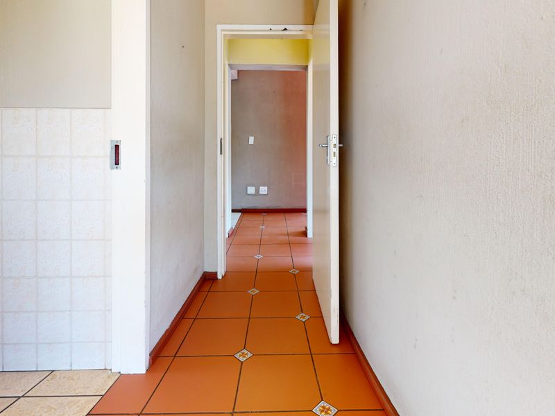 A vacant hallway featuring terracotta-style floor tiles and neutral wall finishes, connecting multiple interior spaces within the townhouse.
