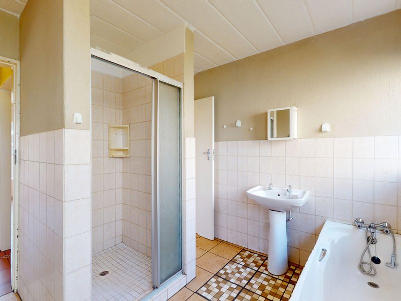 A functional bathroom featuring a pedestal basin, a separate shower enclosure, and a bathtub with tiled wall and floor finishes.