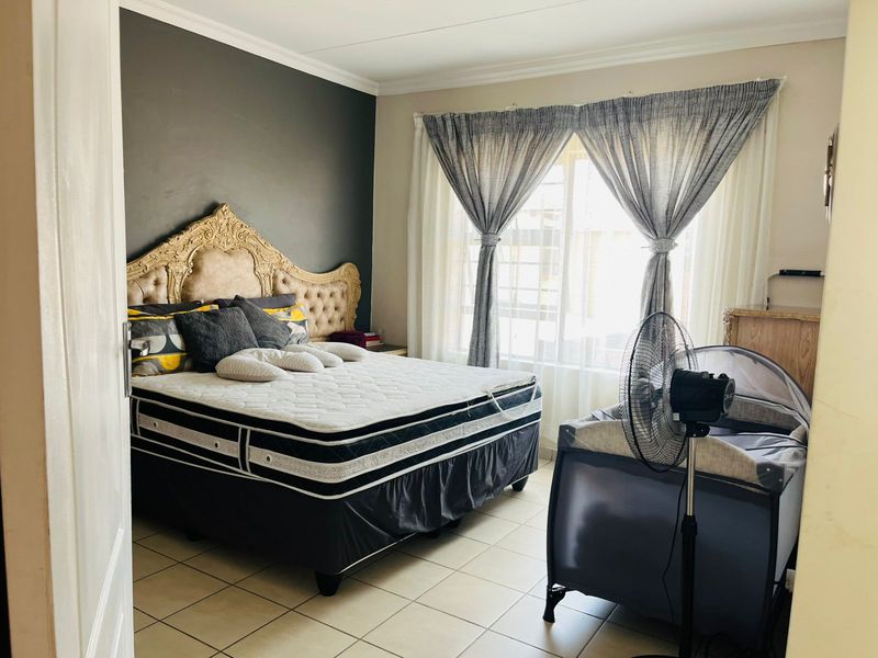 A bedroom featuring tiled flooring and a large window with curtain rails, providing natural light and a neutral backdrop for personalization.
