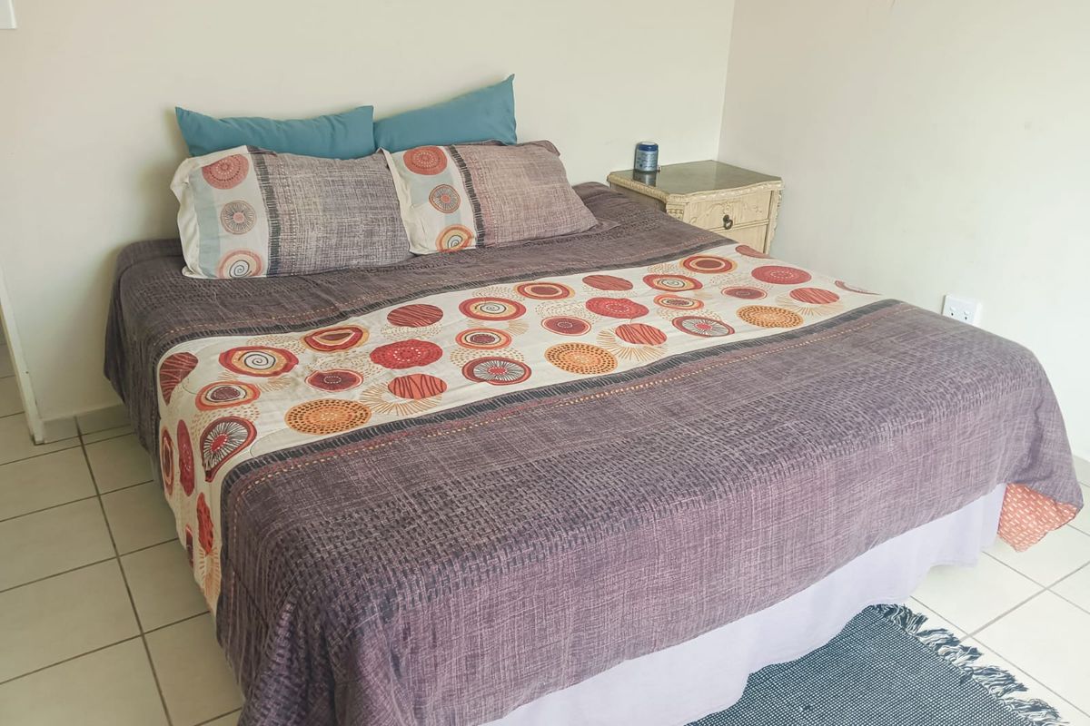 A simple bedroom featuring neutral walls and tiled flooring, providing a functional and clean space for rest.