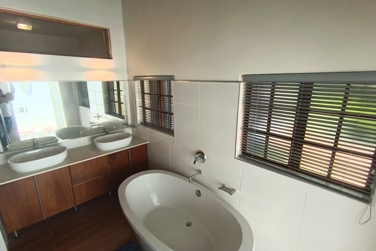 Modern bathroom featuring a freestanding bathtub, dual vessel sinks on a wooden vanity, and large wall-mounted mirrors with tiled walls.