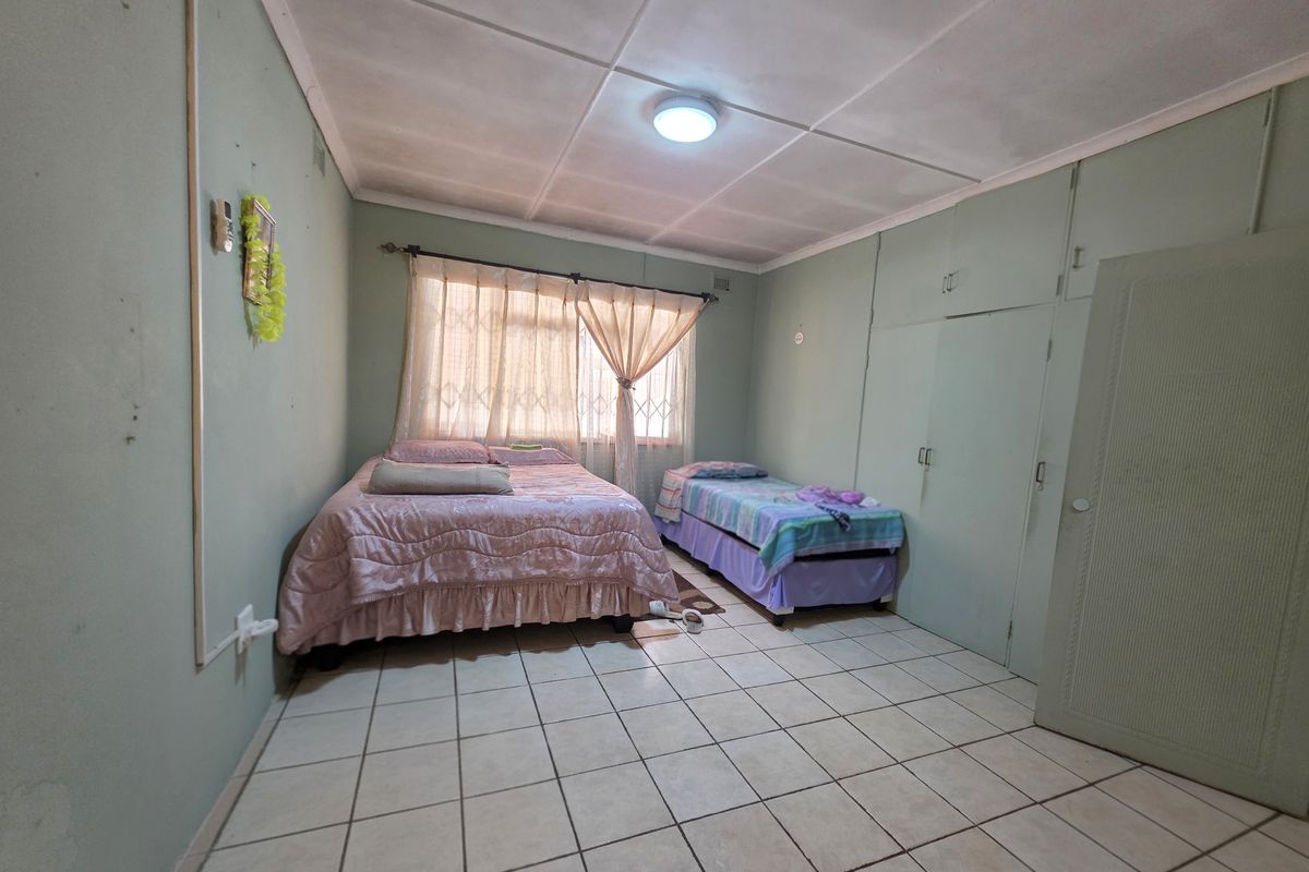 A bedroom featuring tiled flooring, built-in cupboards, and an air conditioning unit, requiring cosmetic updates to improve its overall condition and appeal.