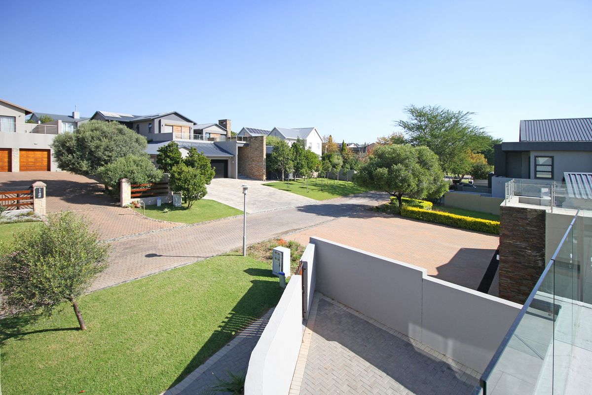 An elevated aerial view of a residential street featuring paved driveways, manicured lawns, and modern architectural elements within a well-maintained estate.