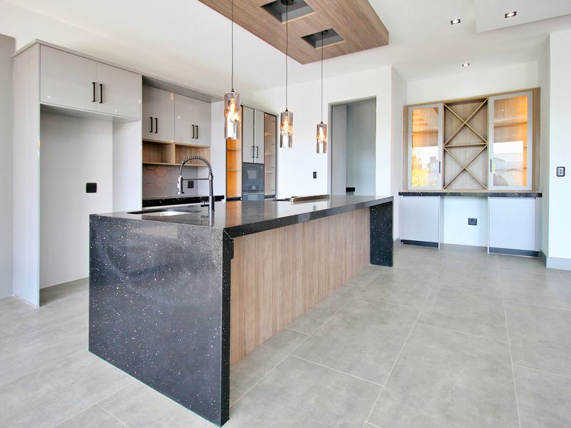 Modern kitchen featuring a large island with stone countertops, sleek cabinetry, integrated wine storage, and contemporary pendant lighting in an open-plan layout.
