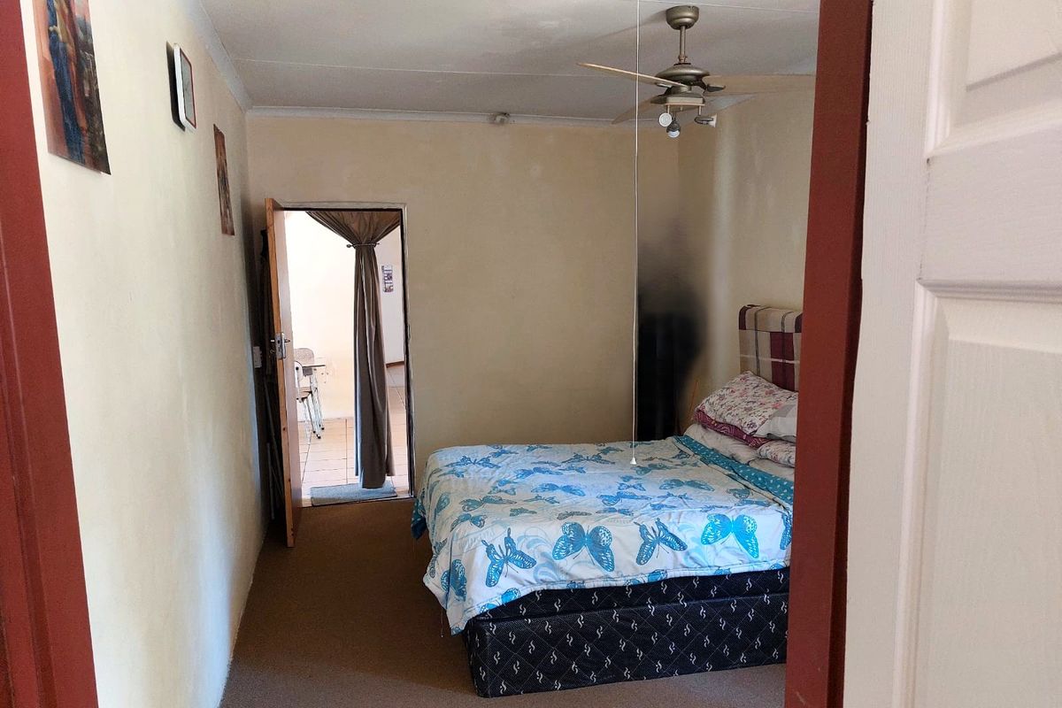 A bedroom featuring carpeted flooring and a ceiling fan, with direct access to an adjoining outdoor area.