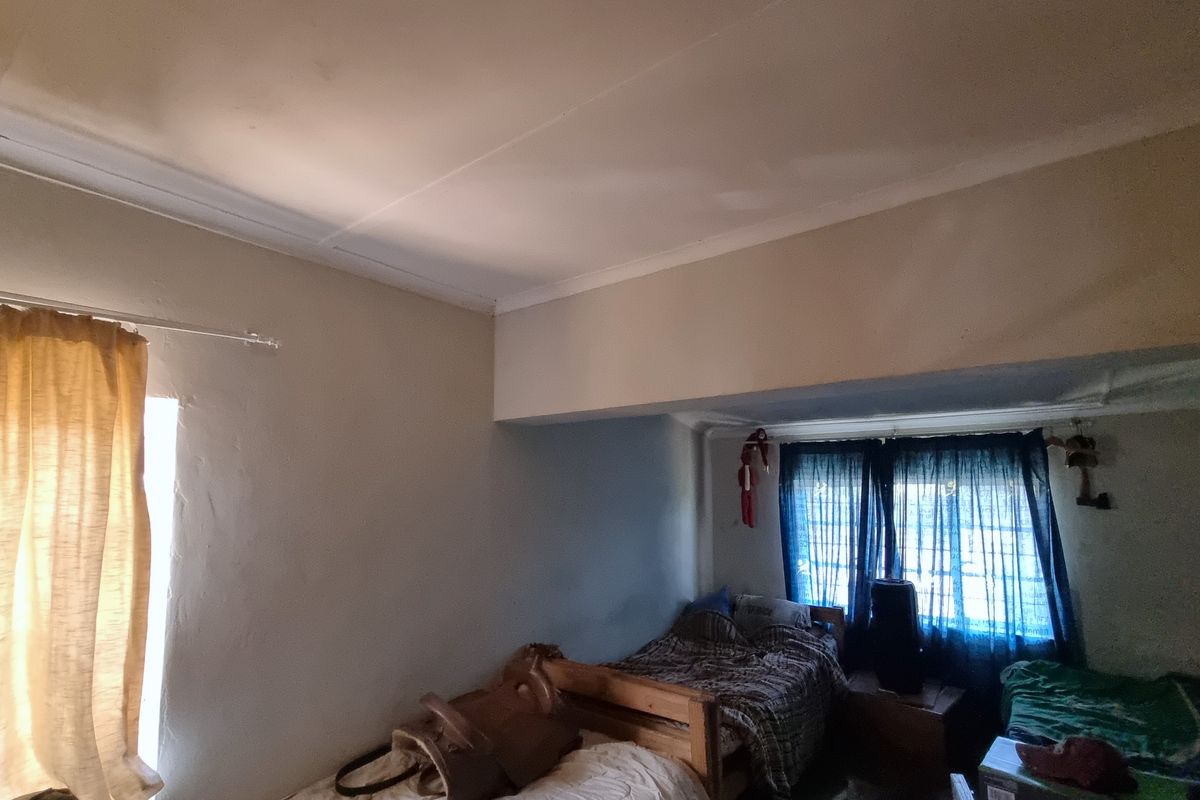 A bedroom featuring a standard layout with ceiling cornicing and window treatments, requiring cosmetic updates to improve the overall finish and appeal.
