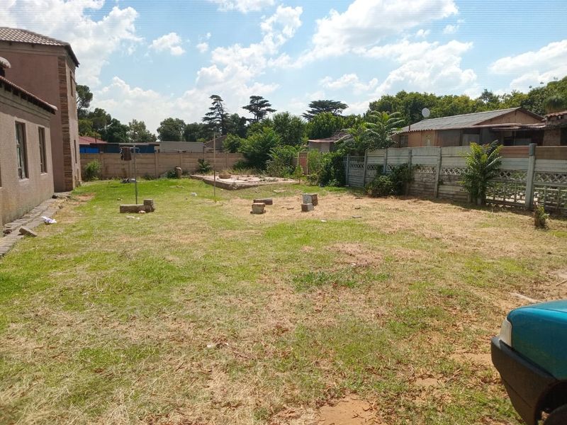 A spacious rear garden area featuring a large lawn and precast concrete boundary walls, offering potential for landscaping and outdoor development.