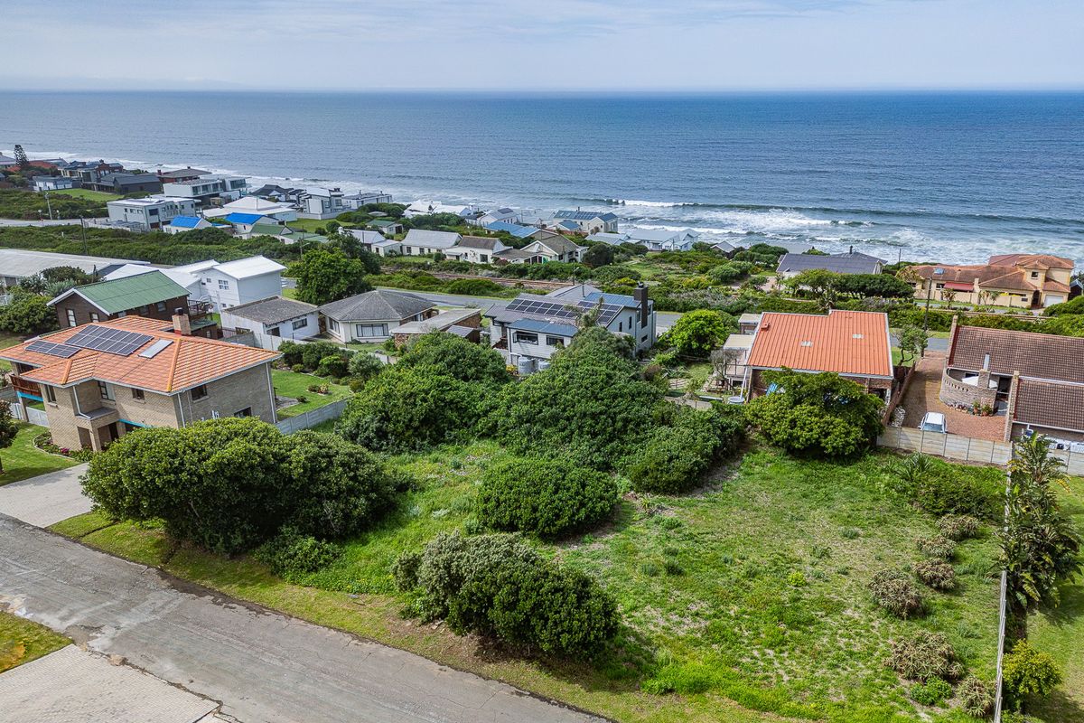 An aerial view of a vacant residential plot situated in a coastal neighborhood, offering potential for development with ocean views.