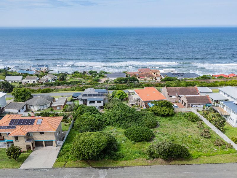 Aerial view of a vacant residential plot situated in a coastal neighborhood with ocean views.