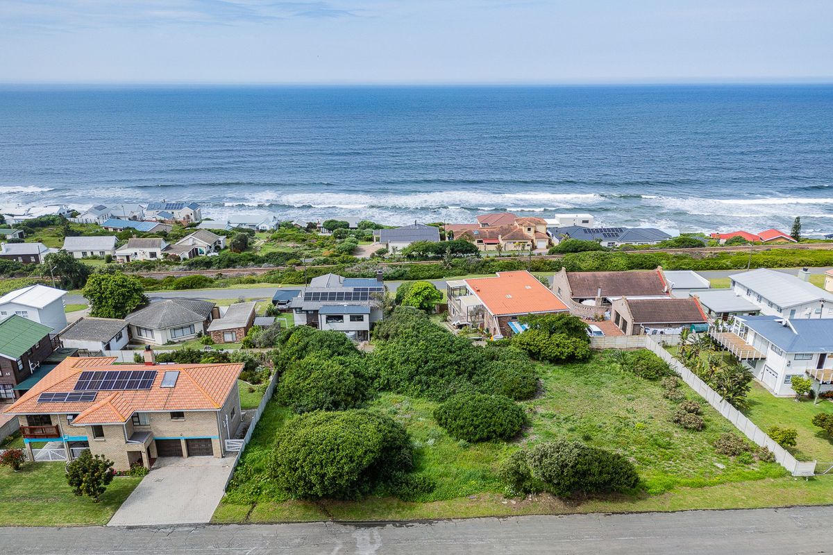 Aerial view of a vacant residential plot situated in a coastal neighborhood with ocean views.