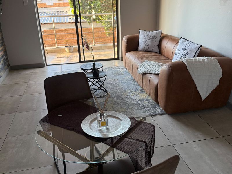 An open-plan living and dining area featuring neutral tiled flooring and a large sliding glass door providing access to a private balcony.