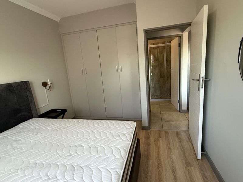 A well-maintained bedroom featuring laminate flooring, built-in cupboards, and direct access to an en-suite bathroom.
