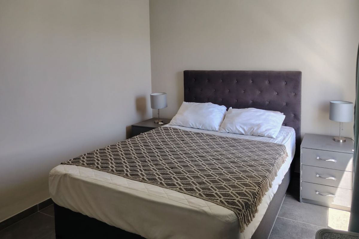 A neutrally painted bedroom featuring tiled flooring and a coved ceiling, providing a clean and functional space.