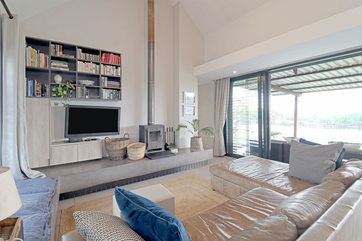 Spacious living room featuring a vaulted ceiling, a modern freestanding fireplace with a concrete hearth, built-in shelving, and large sliding doors leading to the patio.