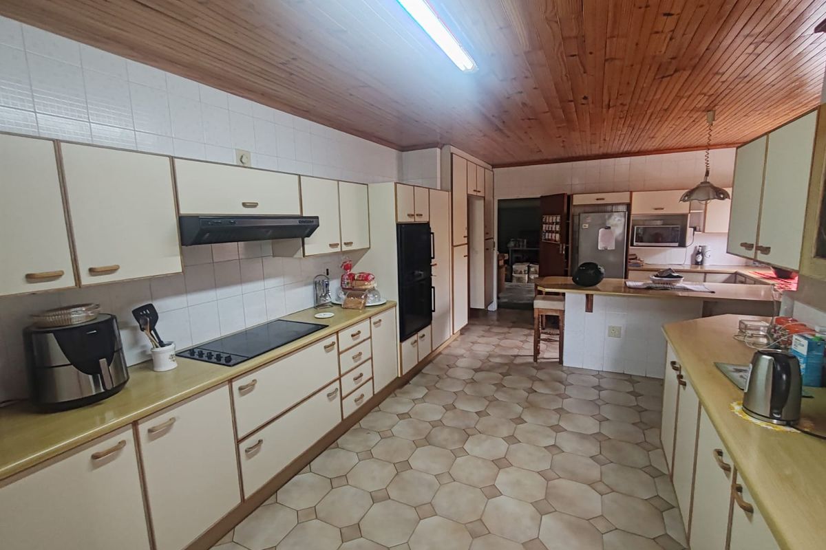 Spacious kitchen featuring extensive built-in cabinetry, laminate countertops, integrated appliances, and a distinctive timber tongue and groove ceiling.