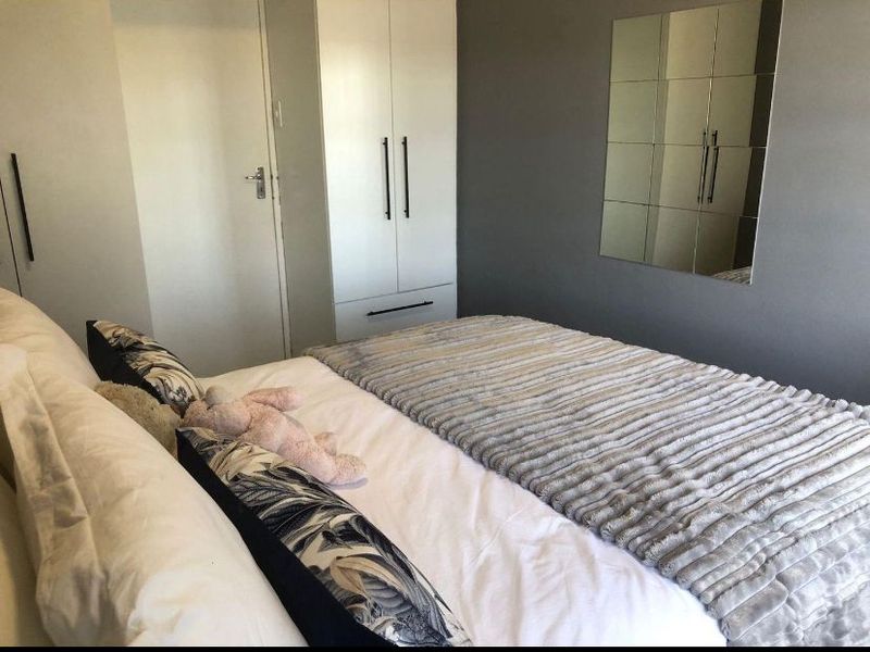 A well-maintained bedroom featuring built-in cupboards and a decorative mirrored wall panel, offering a clean and functional living space.