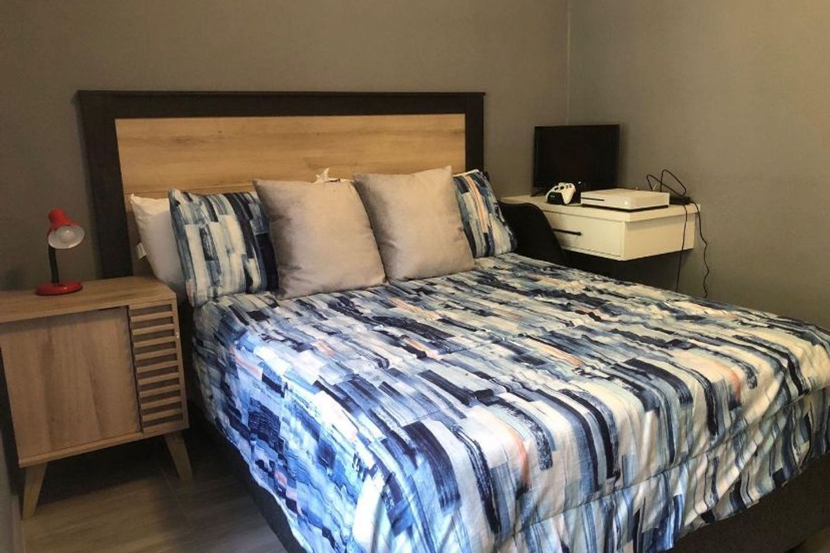 A bedroom featuring tiled flooring and neutral wall paint, providing a functional space for rest.