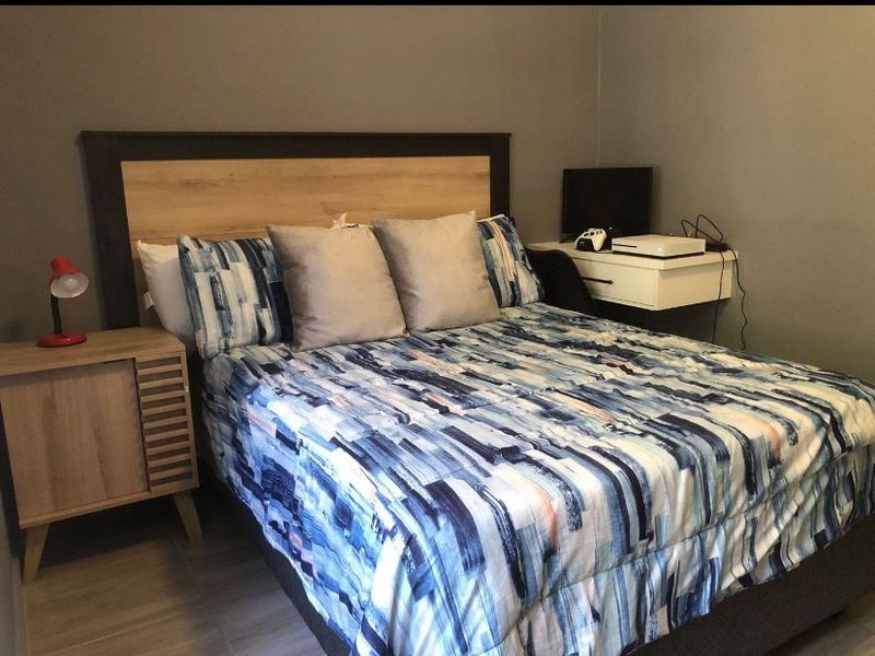 A bedroom featuring tiled flooring and neutral wall paint, providing a functional space for rest.