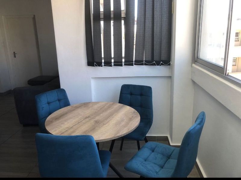 A dining area featuring tiled flooring, vertical blinds, and aluminium window frames, providing a functional space for meals.