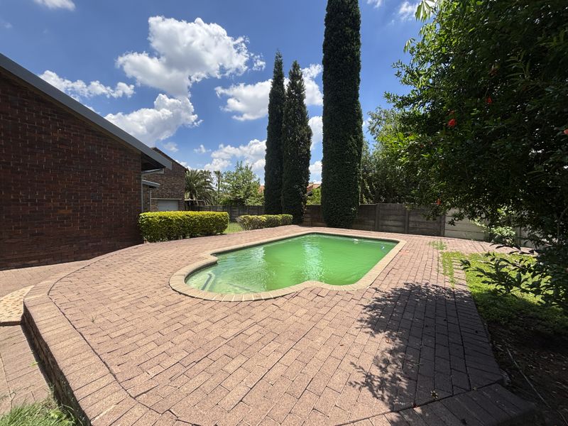 Outdoor pool area featuring brick paving and a swimming pool, set against a brick house exterior and perimeter walling.