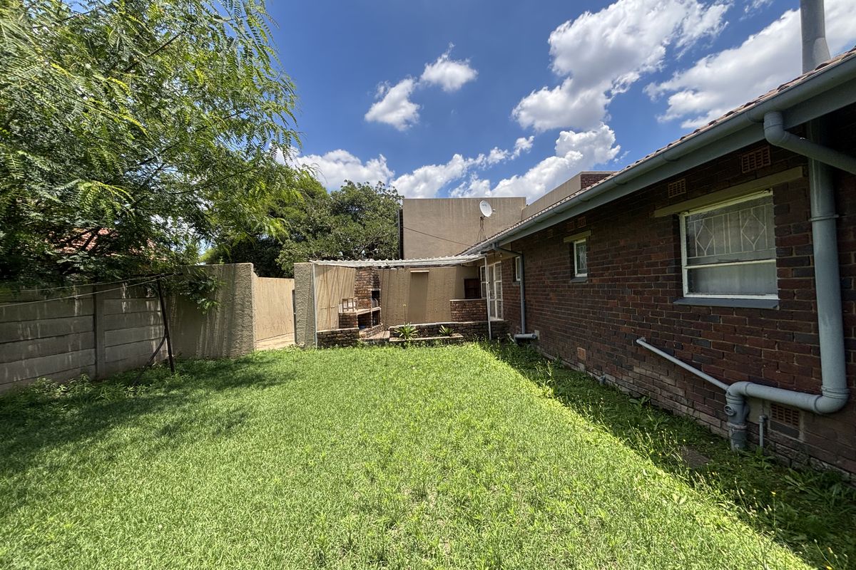 Rear garden area featuring a brick exterior, built-in braai, and perimeter walling, offering potential for outdoor entertainment space development.