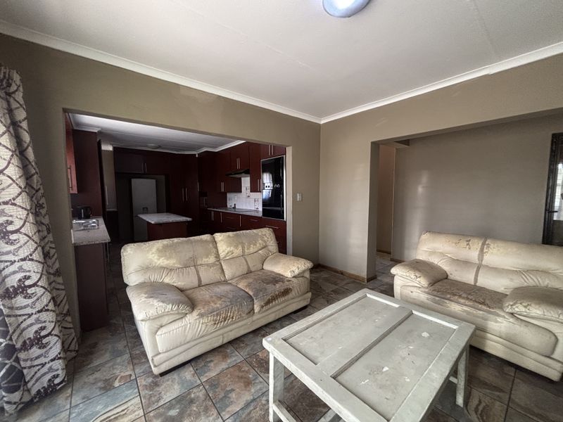 Open-plan living area featuring tiled flooring and a connected kitchen with dark wood cabinetry, stone countertops, and integrated oven.