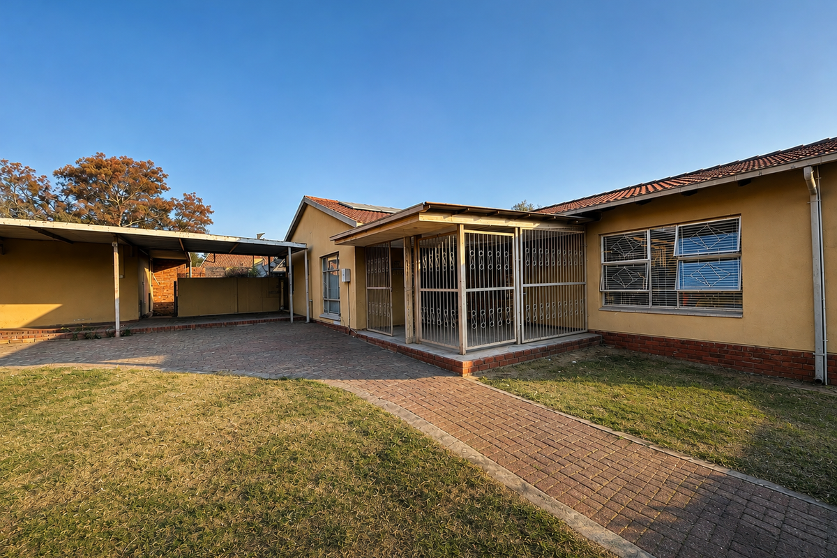 Rear view of the property featuring a paved courtyard, covered carport, and secure entrance with security gates and bars.