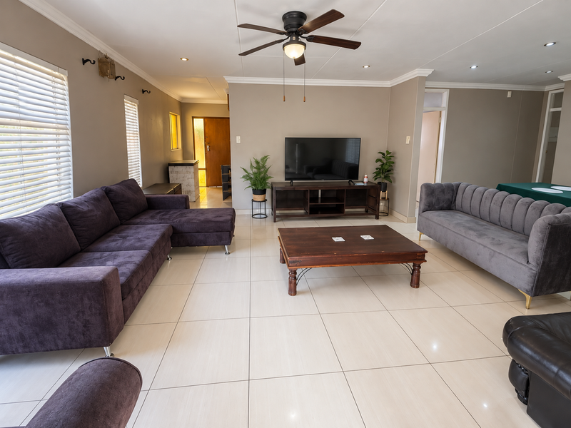 Spacious living room featuring neutral tiled flooring, recessed lighting, a ceiling fan, and large windows with venetian blinds.