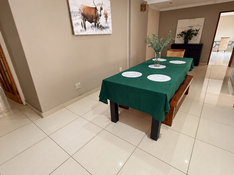 A bright dining area featuring neutral wall tones, crown molding, recessed downlighting, and large format polished floor tiles.