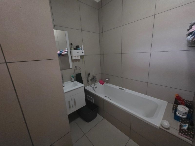 A modern bathroom featuring large-format wall tiles, a built-in bathtub, and a vanity unit with an integrated washbasin.