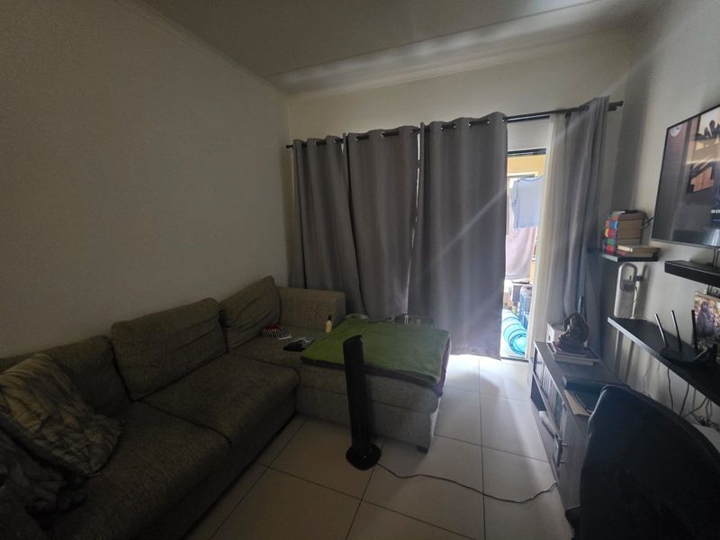 A living room featuring tiled flooring and a sliding door providing access to an outdoor area.