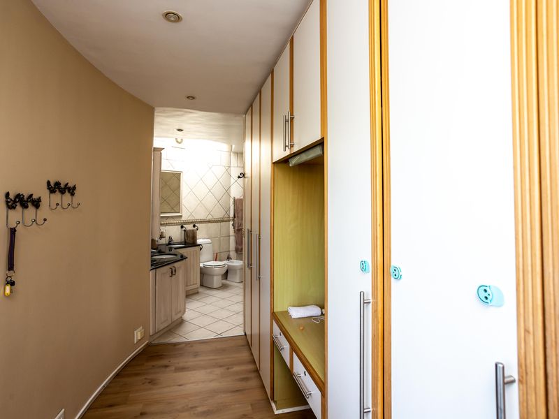 A hallway featuring extensive built-in cabinetry and storage, leading into a tiled bathroom equipped with a vanity, toilet, and bidet.