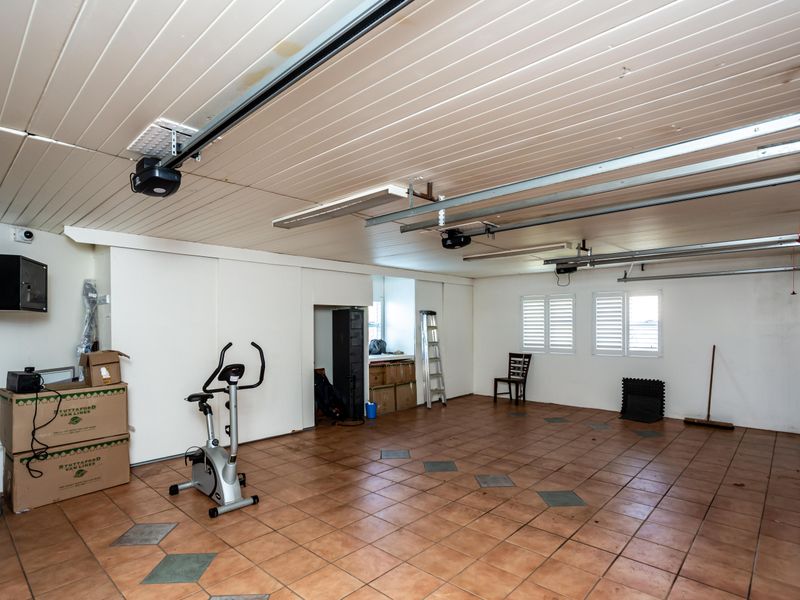 Spacious double garage featuring tiled flooring, timber ceiling, and integrated garage door motors, providing ample storage or parking space.