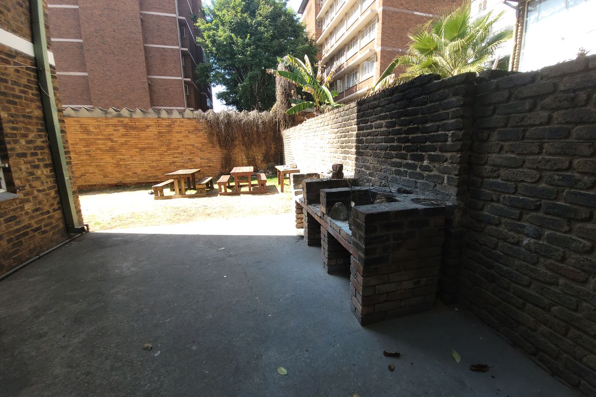 Rear outdoor area featuring a built-in brick braai, concrete patio space, and brick boundary walls in a communal residential setting.
