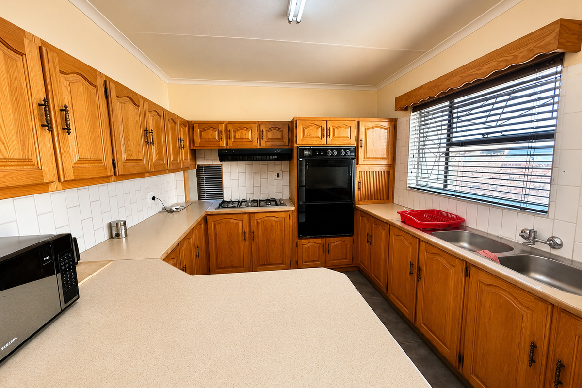 A functional kitchen featuring traditional wooden cabinetry, laminate countertops, a built-in oven, gas hob, and a double basin sink with tiled backsplash.