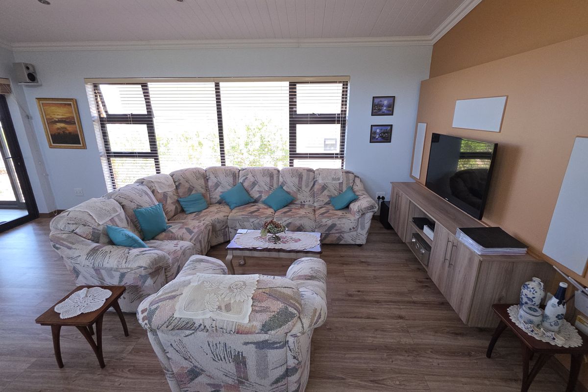 Spacious living room featuring wood-look laminate flooring, large windows with blinds, and a built-in media console unit.