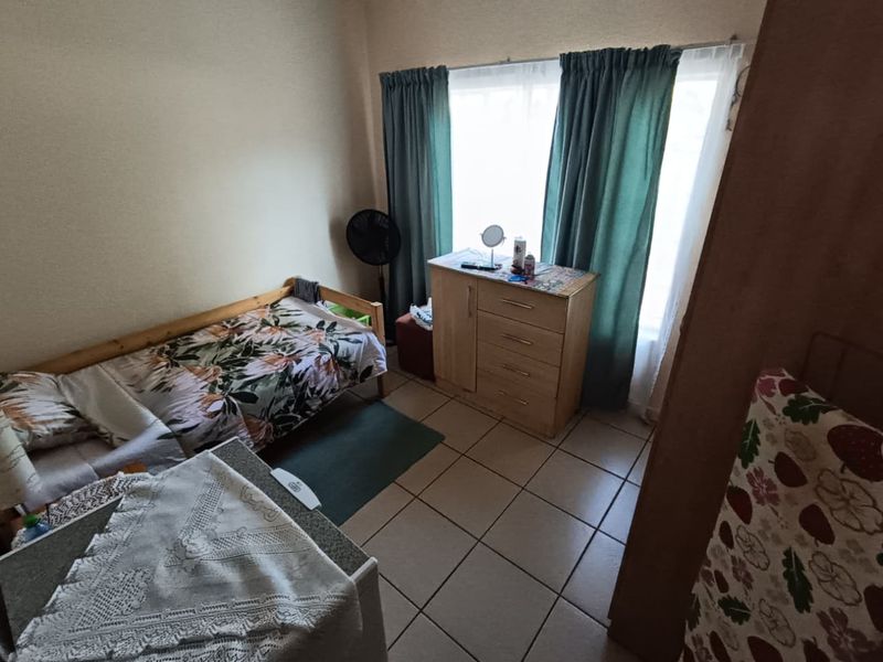 A functional bedroom featuring tiled flooring and a large window that allows for natural light.