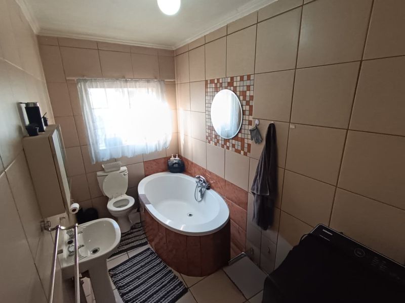 A functional bathroom featuring a pedestal basin, toilet, and a freestanding bathtub with full-height wall tiling.