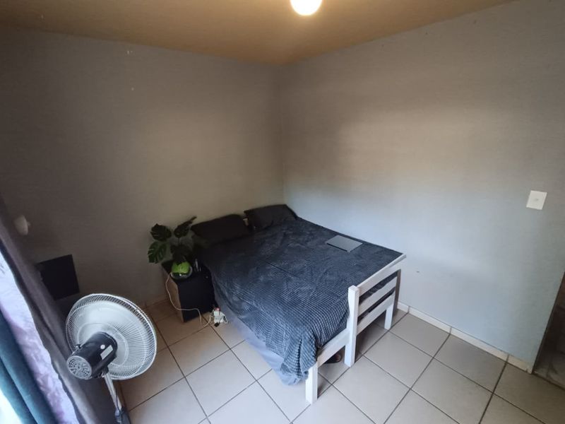 A compact bedroom featuring tiled flooring and neutral wall finishes, providing a functional space ready for personalization and cosmetic updates.