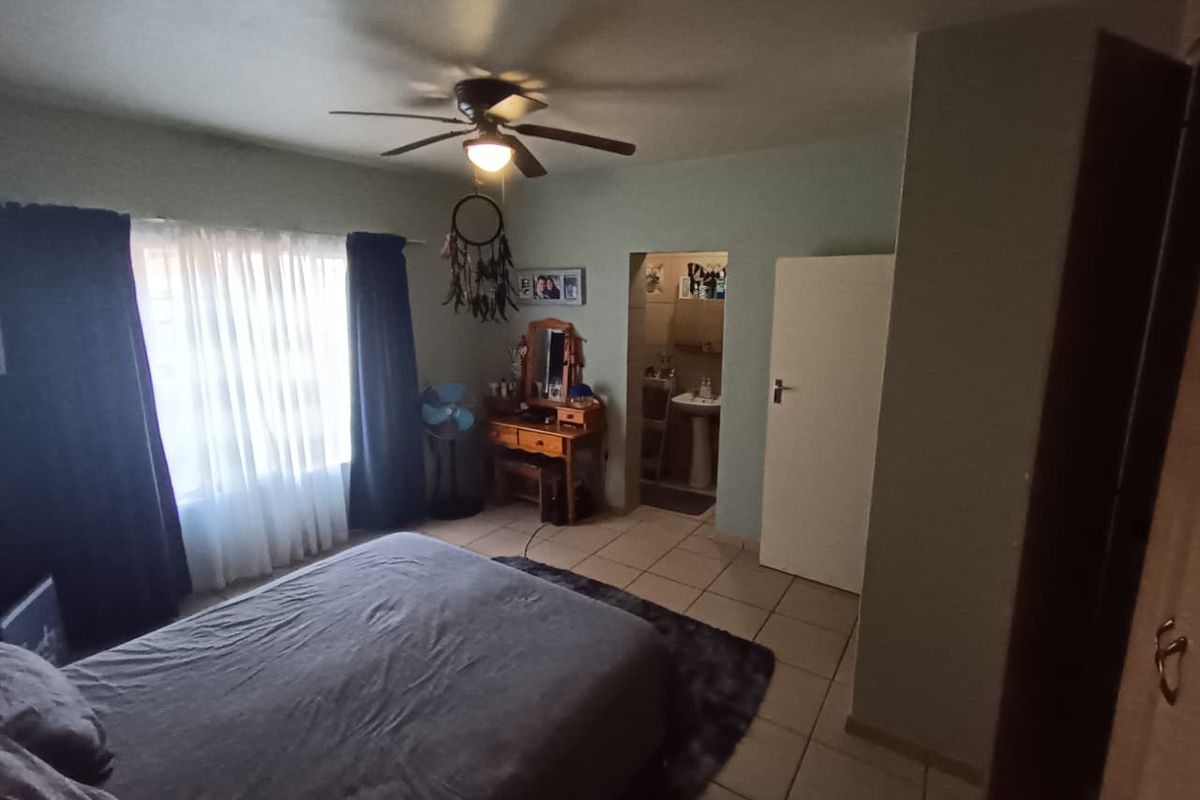 A bedroom featuring tiled flooring, a ceiling fan, and direct access to an en-suite bathroom.