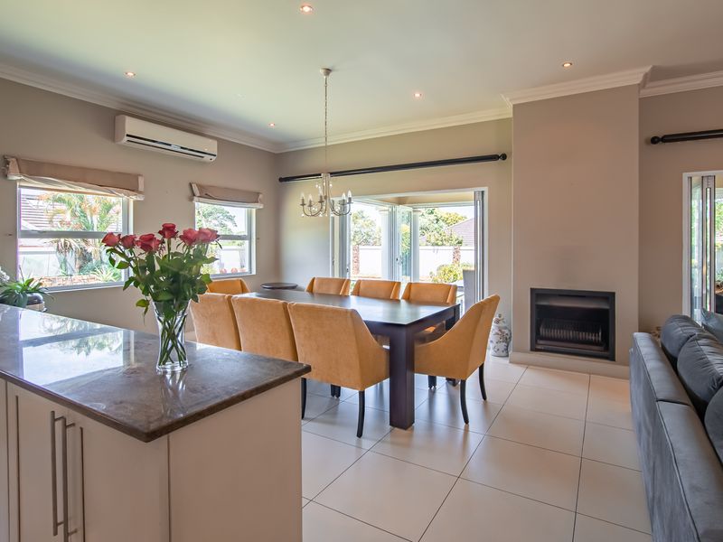 Spacious open-plan living and dining area featuring tiled floors, a built-in fireplace, and seamless access to the outdoor patio through folding glass doors.