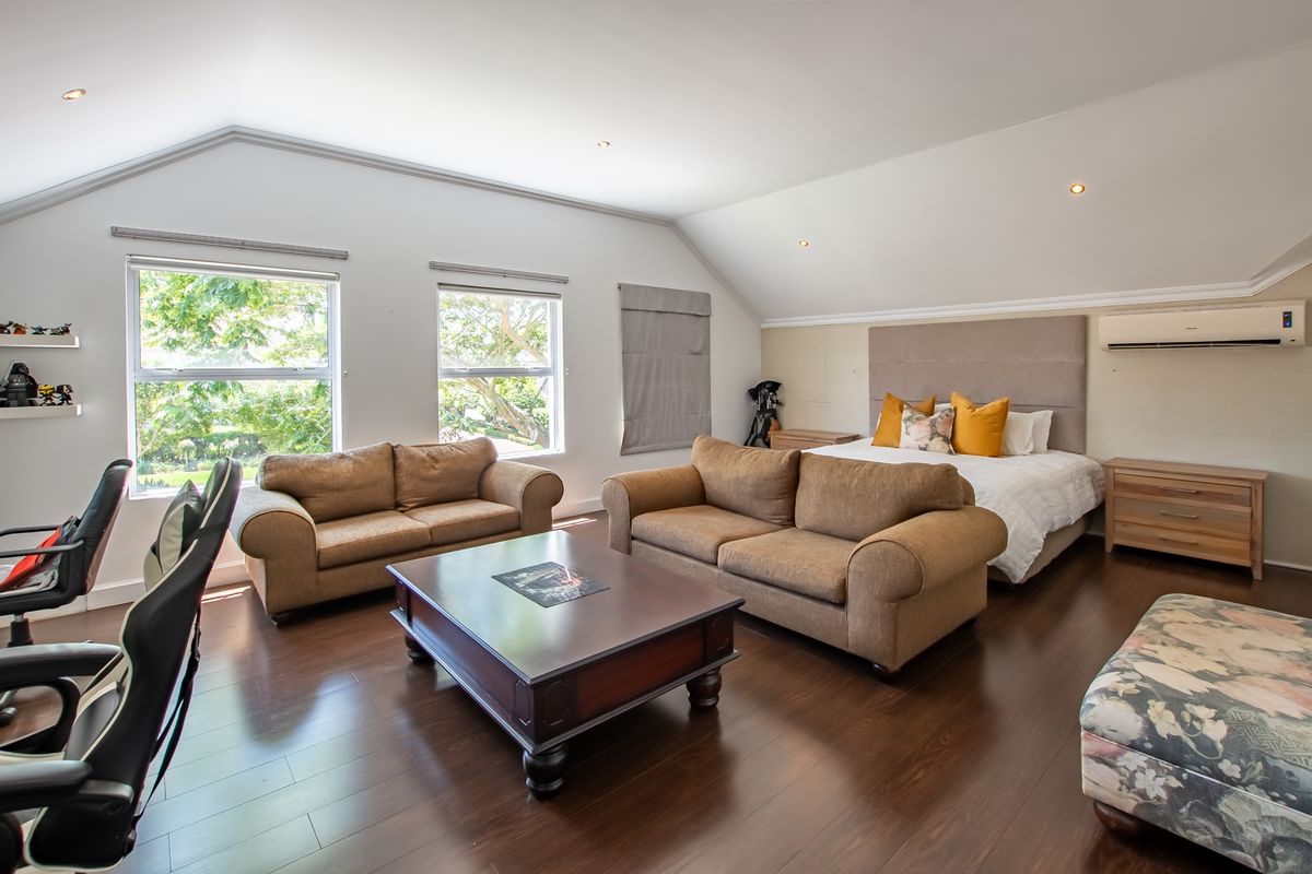 Spacious bedroom featuring laminate flooring, recessed lighting, a split-system air conditioner, and a built-in headboard with large windows providing natural light.