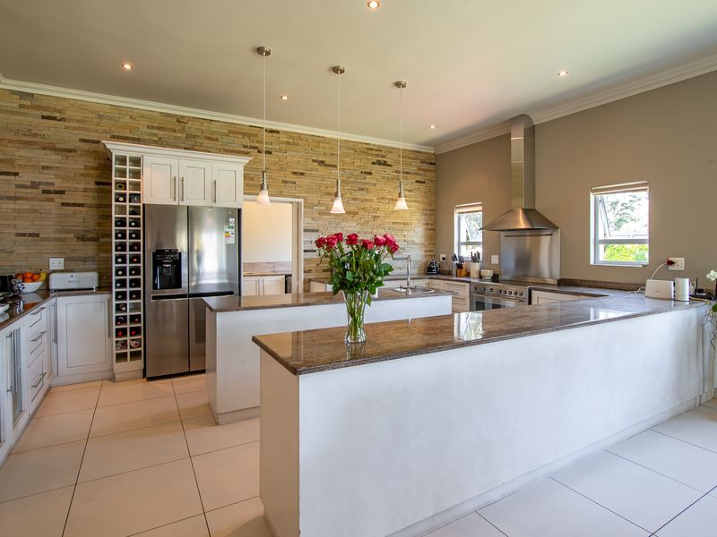 Modern kitchen featuring a stone veneer accent wall, granite countertops, a central island, and integrated stainless steel appliances with ample cabinetry.