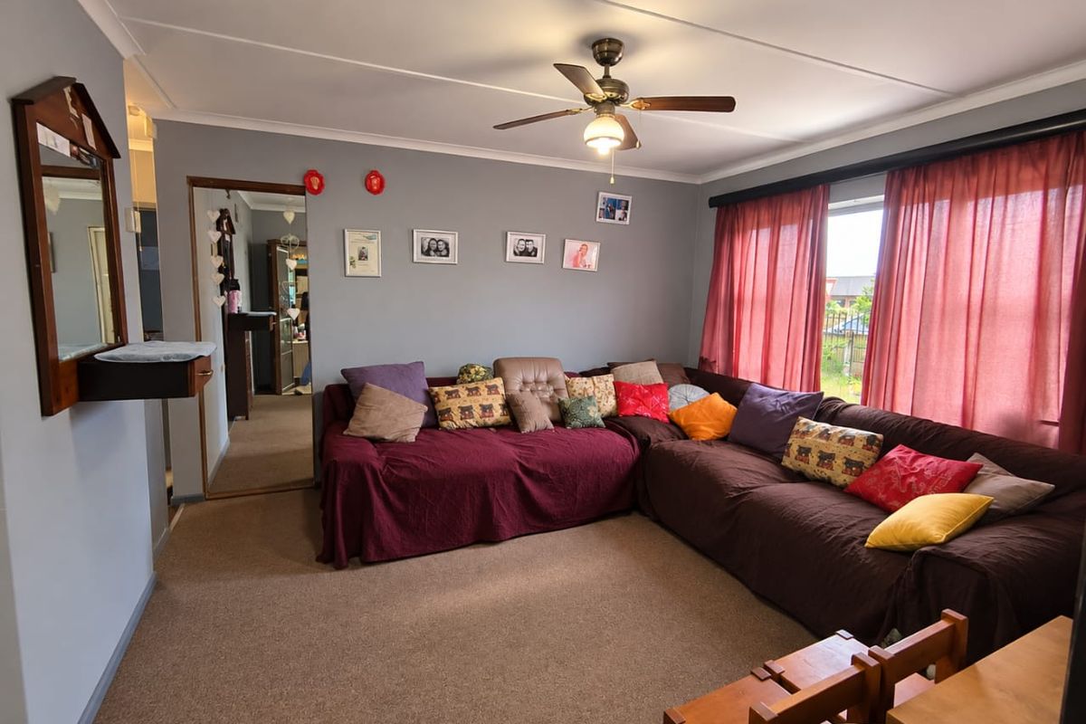 A comfortable living room featuring carpeted flooring, a ceiling fan, and coved ceilings, providing a functional and lived-in space.