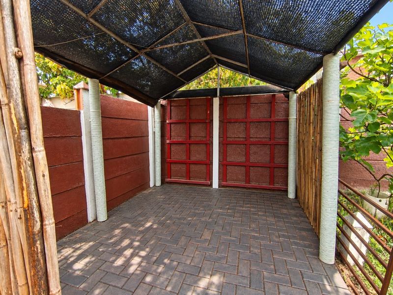 A covered outdoor patio area featuring paved flooring, a shade cloth canopy, and decorative boundary walls, suitable for an outdoor seating or entertainment space.