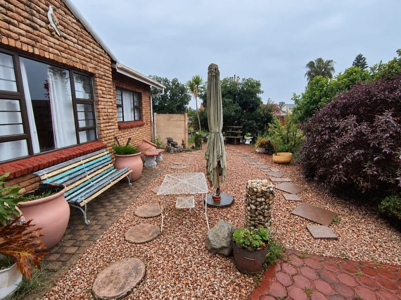A rear garden area featuring a face brick facade, paved patio section, and gravel landscaping with stepping stones.
