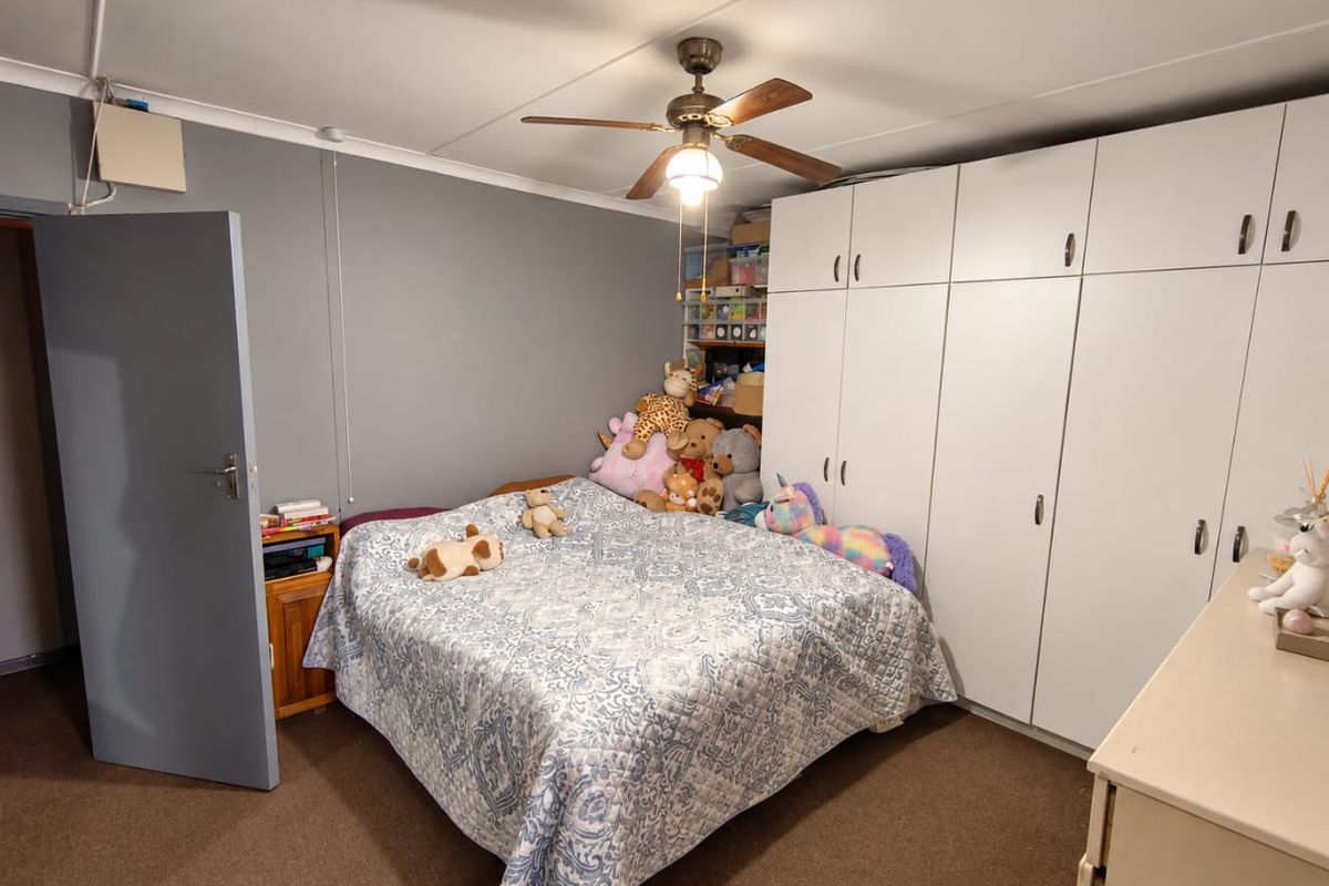 A bedroom featuring extensive built-in floor-to-ceiling cupboards, a ceiling fan, and neutral wall finishes.