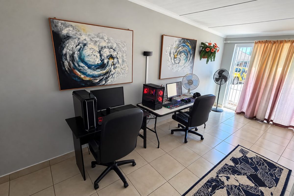A functional living area featuring tiled flooring and a sliding glass door with security gate, providing access to the exterior.